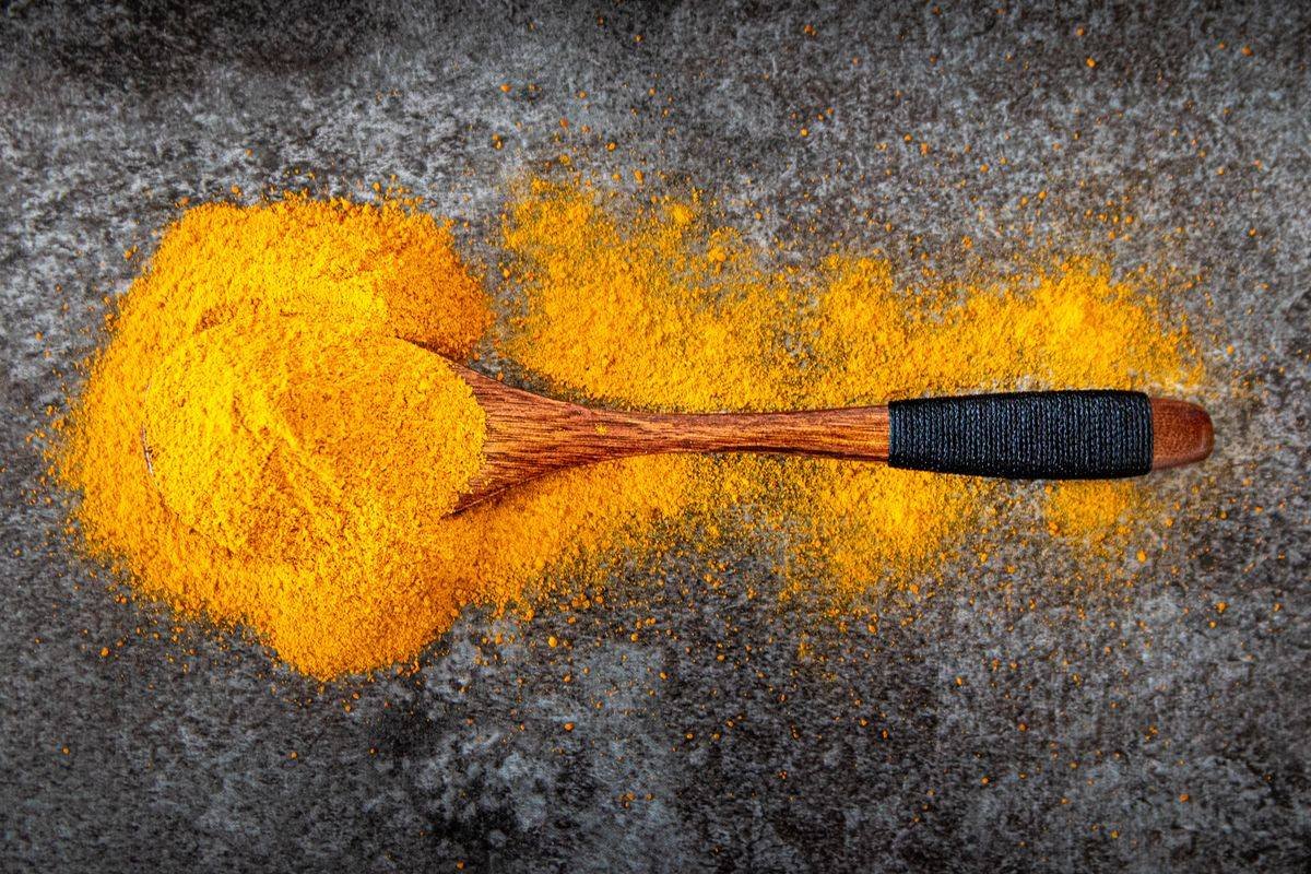 Curcuma in polvere con cucchiaio di legno