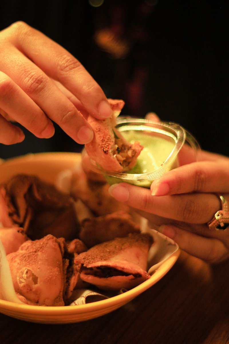 Samosa intinta in un chutney verde