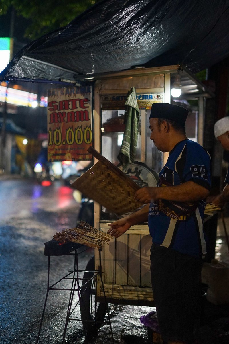 Venditore di satay che griglia gli spiedini al mercato notturno