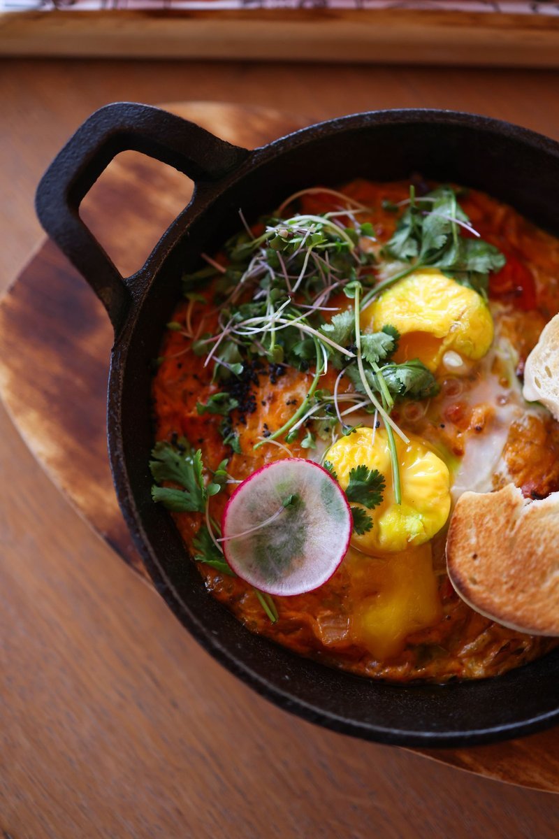 Padella di shakshuka con uova, erbe fresche e pane